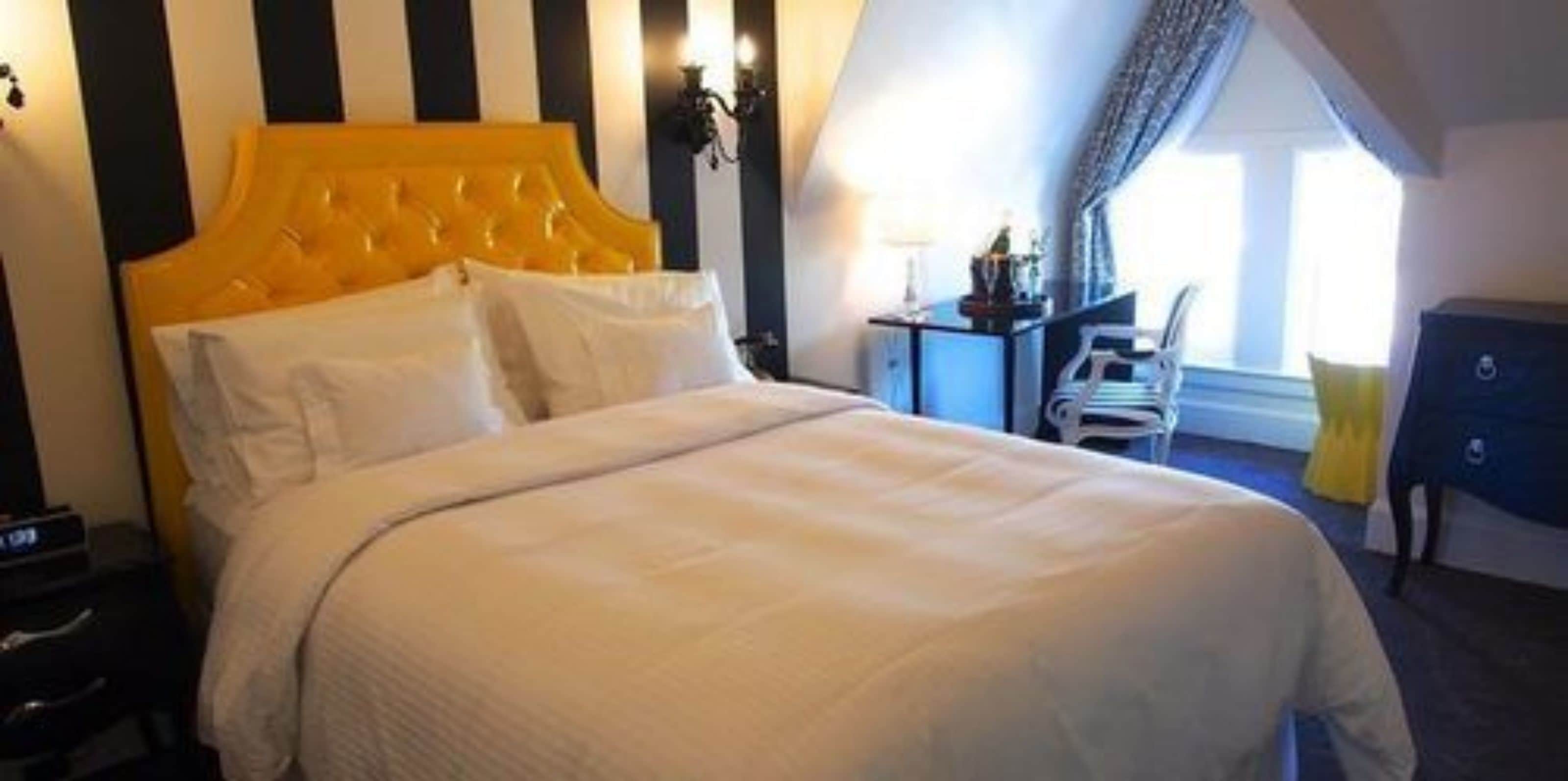 Une chambre d’hôtel avec un grand lit, une table de chevet, un bureau et une chaise.