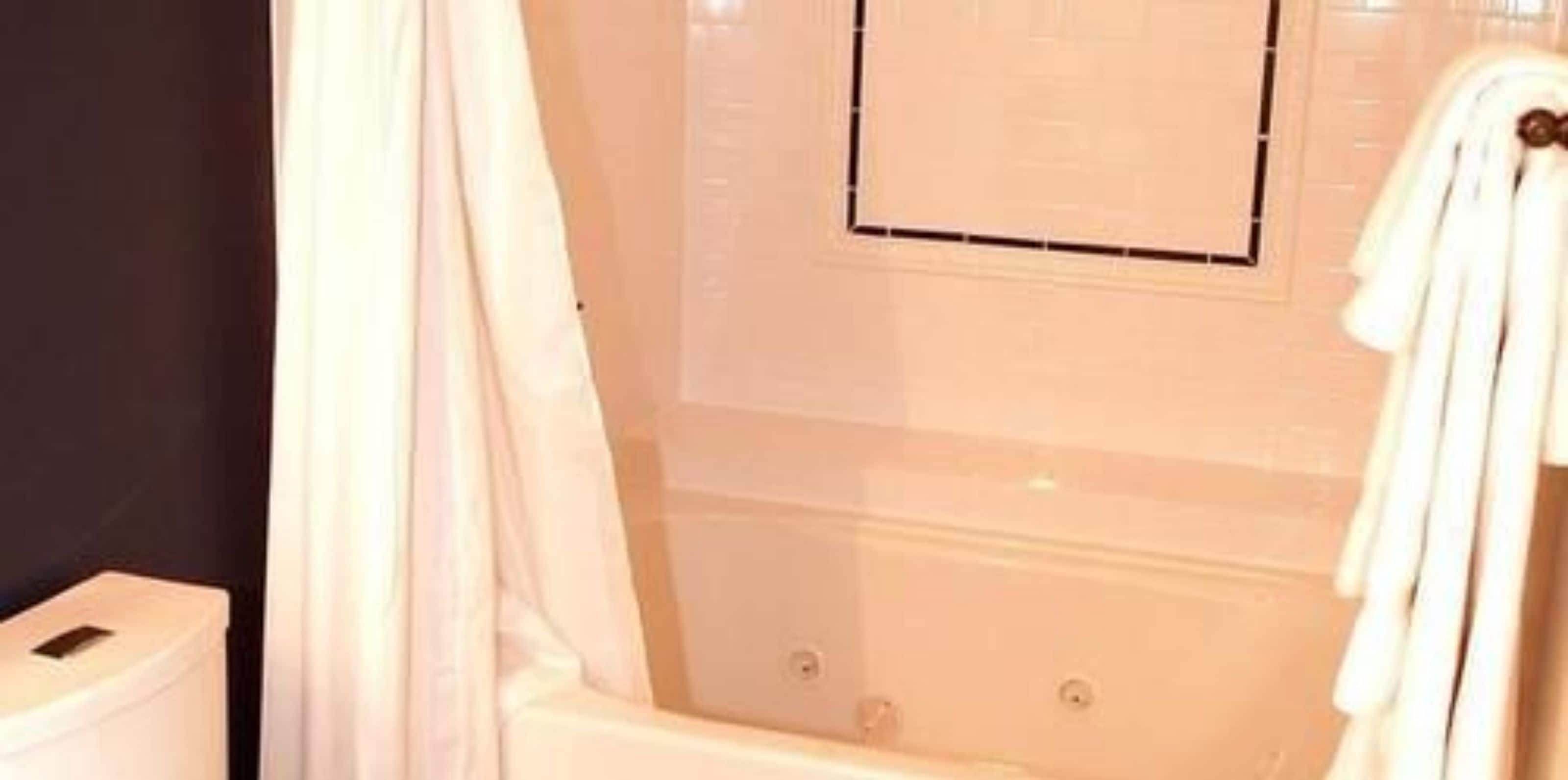 A bathroom with a bathtub, a toilet, and a shower curtain.