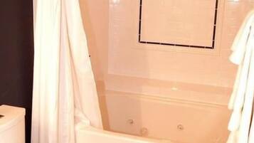 A bathroom with a bathtub, a toilet, and a shower curtain.