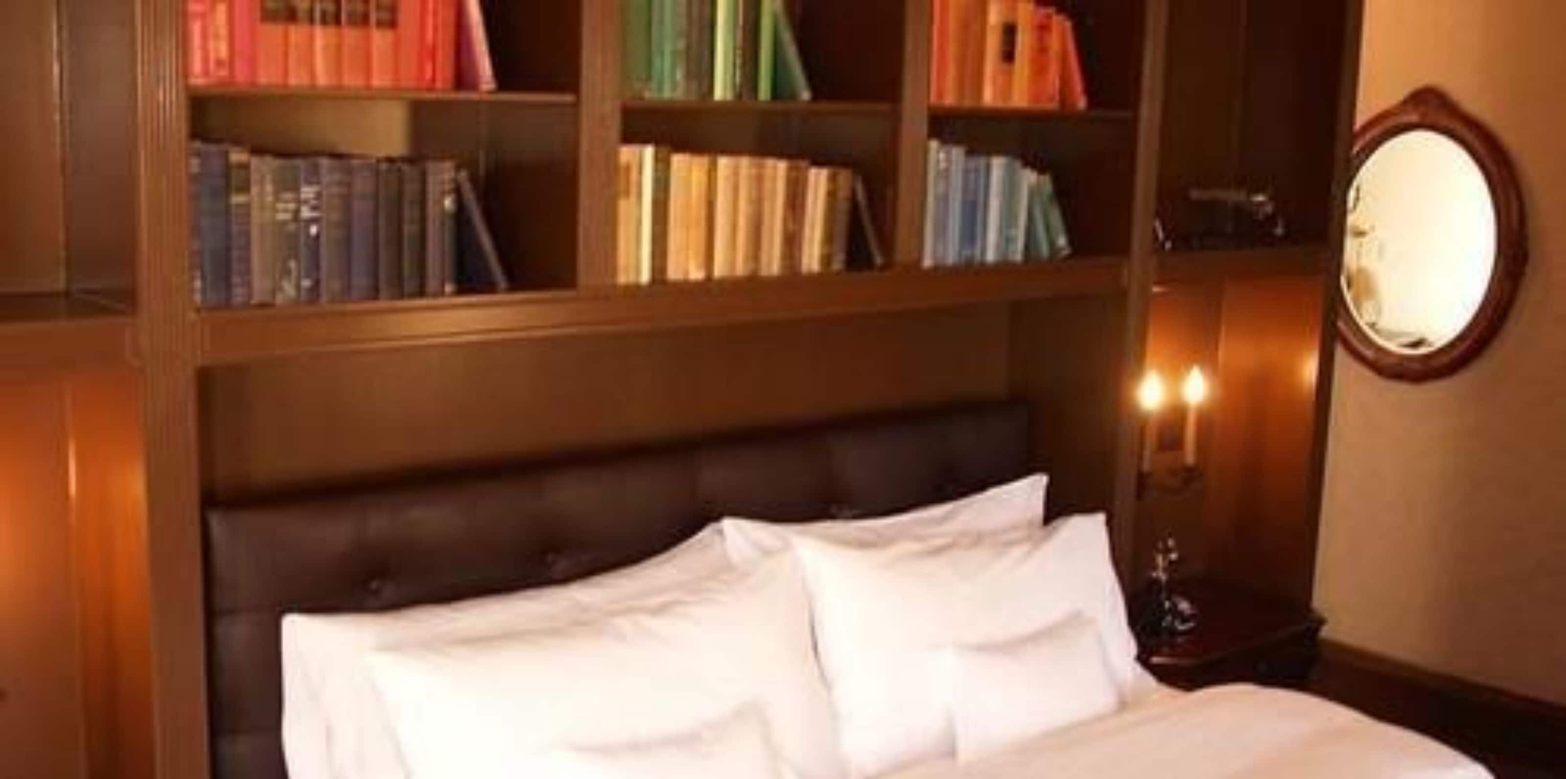 Een slaapkamer met een groot bed, een houten hoofdbord en een boekenkast vol boeken.