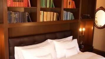 Een slaapkamer met een groot bed, een houten hoofdbord en een boekenkast vol boeken.