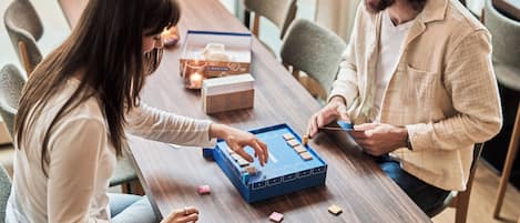 A wooden table with a board game, a candle, and a box of tissues.