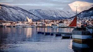 Un port avec des bateaux, une église et des montagnes en arrière-plan.