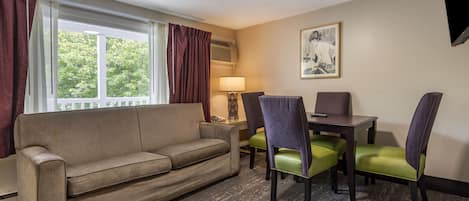 A hotel room with a sofa, two chairs, a table, and a lamp.
