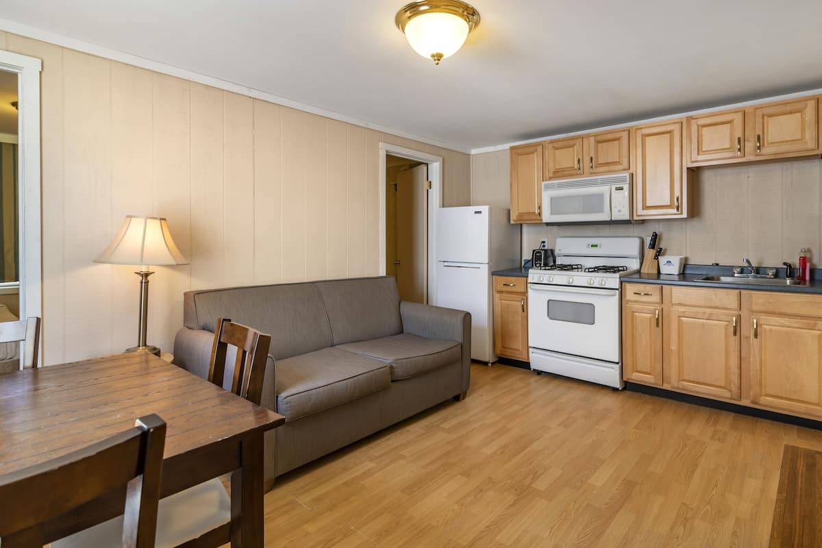 A compact kitchen with wooden cabinets, a microwave, a stove, and a refrigerator.