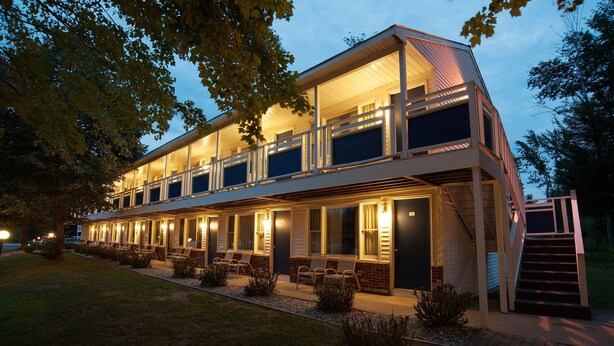A modern two-story building with a covered outdoor seating area and a staircase leading to the entrance. - Anchor Inn and Cottages Wells-Ogunquit (Wells)