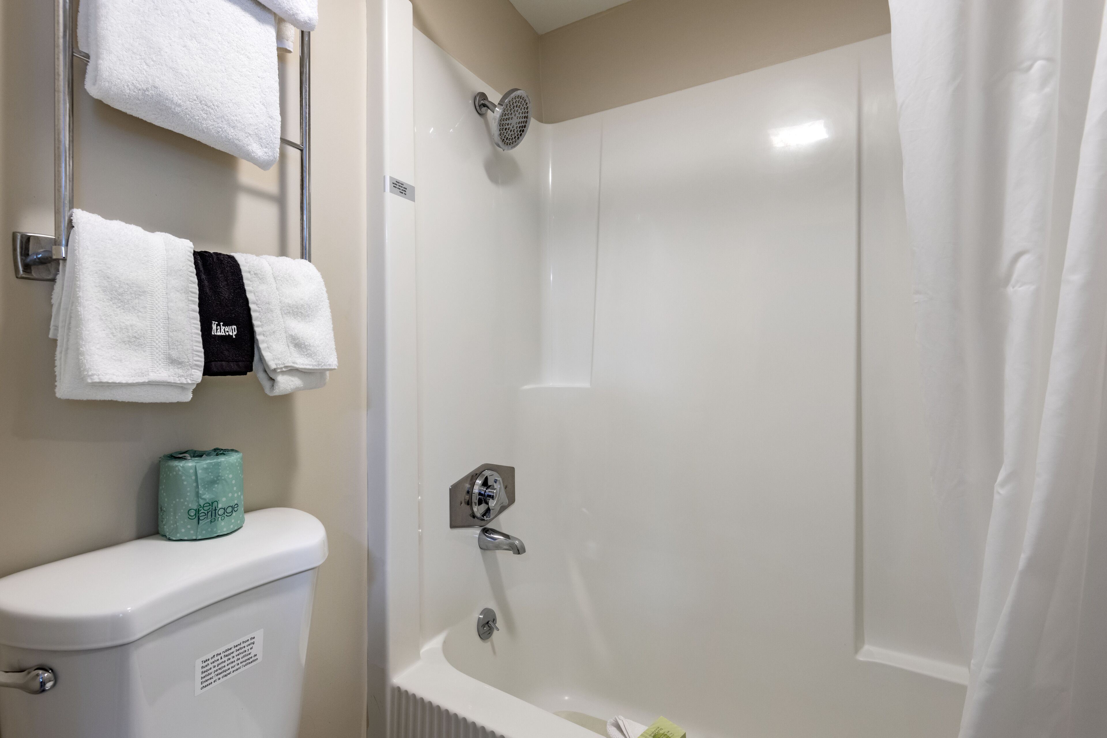 A bathroom with a toilet, a shower, and a bathtub. There are towels hanging on a rack above the toilet.
