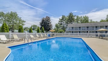 Una piscina al aire libre de temporada, sombrillas