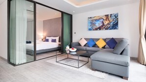Un salon moderne avec un canapé gris, une cloison en verre et un tableau accroché au mur.