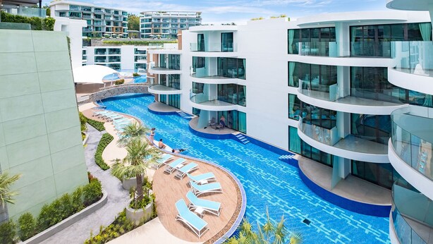 Un hôtel moderne doté d’une grande piscine intérieure, de nombreux balcons et d’un espace paysager aménagé autour de la piscine.