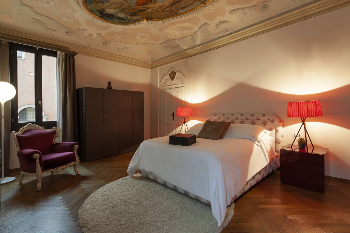 Una camera da letto con un letto grande, un armadio, una sedia e una lampada.