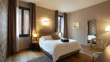 A hotel room with a large bed, a desk, a chair, and a window with curtains.