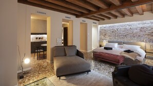A modern bedroom with a stone wall, a sofa, a bed, and a dining area with a table and chairs. - Hotel Corte di Gabriela (Venice)