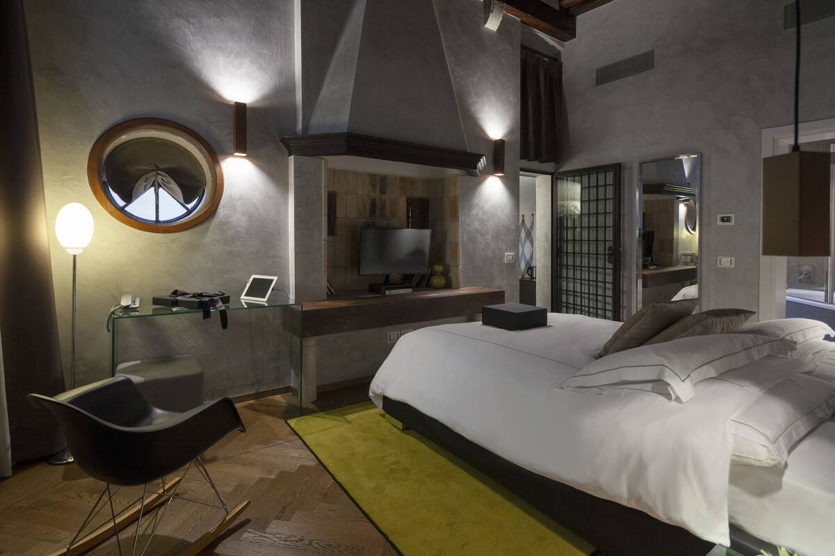 Una camera da letto moderna con un letto grande, una scrivania con un computer, una sedia e uno specchio rotondo.
