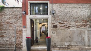A building entrance with a double door, a doormat, and two large flower pots. - Hotel Corte di Gabriela (Venice)