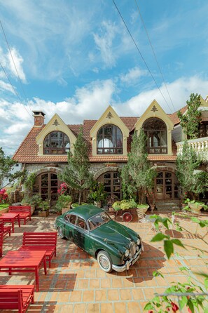 A vintage green car parked in front of a house with a tiled roof and arched windows. - Saphir Dalat Hotel (Da Lat)