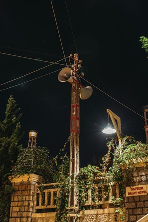 A utility pole with multiple wires and a street lamp, surrounded by greenery and a stone building with a sign reading "Saphir Dalat Hotel". - Saphir Dalat Hotel (Da Lat)