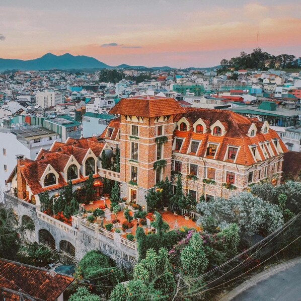 A large, historic building with a courtyard, surrounded by a dense urban area and mountains in the background. - Saphir Dalat Hotel (Da Lat)