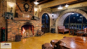 Un hall d’hôtel accueillant, avec une cheminée en briques, des meubles en bois et des arches en pierre.