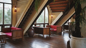 Une pièce dotée d’un plancher en bois, de sièges rembourrés de couleur rouge et d’un grand vase contenant une plante.