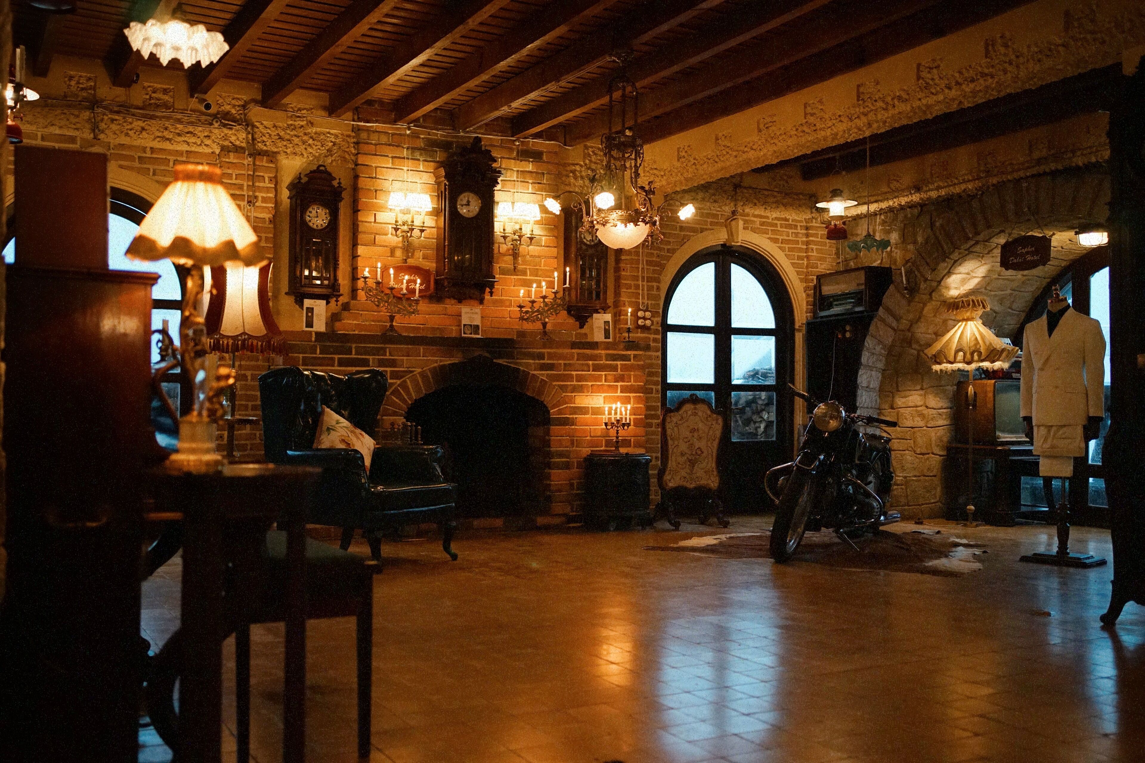 A dimly lit room with a fireplace, vintage furniture, and a motorcycle.