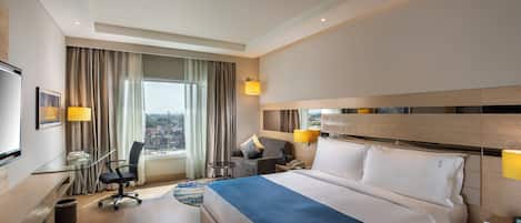 Una habitación de hotel con cama, escritorio, silla y vistas a la ciudad.