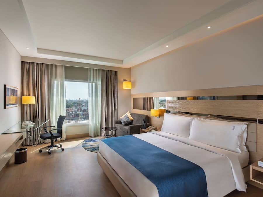 Una habitación de hotel con cama, escritorio, silla y vistas a la ciudad.