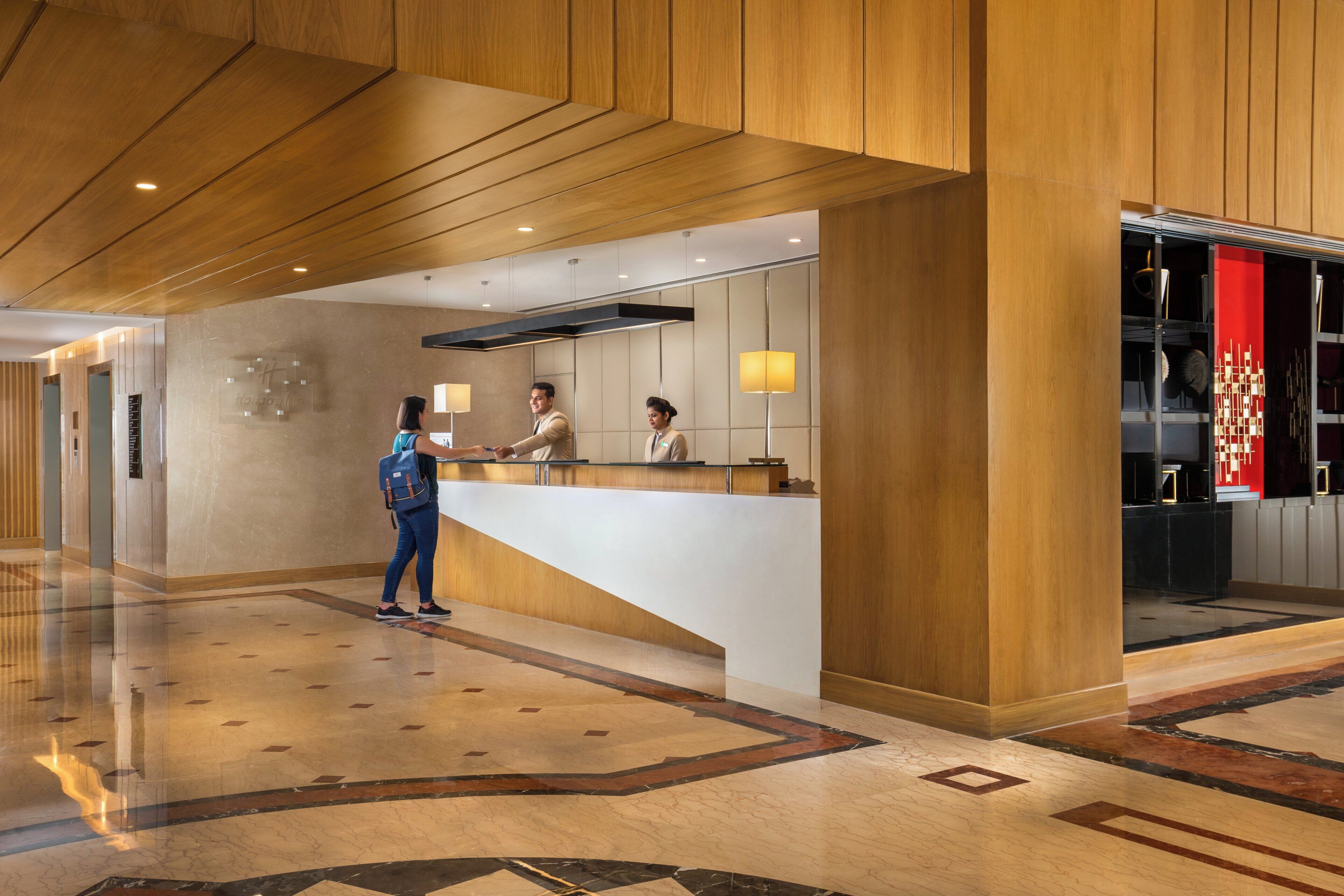 A reception area with a wooden reception desk, a glass partition, and a floor with a geometric pattern.