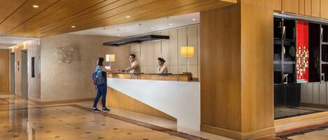 A reception area with a wooden reception desk, a glass partition, and a floor with a geometric pattern.