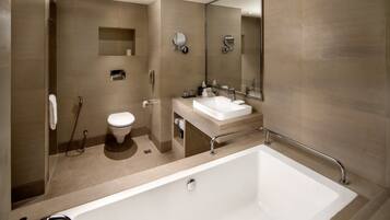 Un baño moderno con bañera, inodoro, lavabo y un espejo grande.