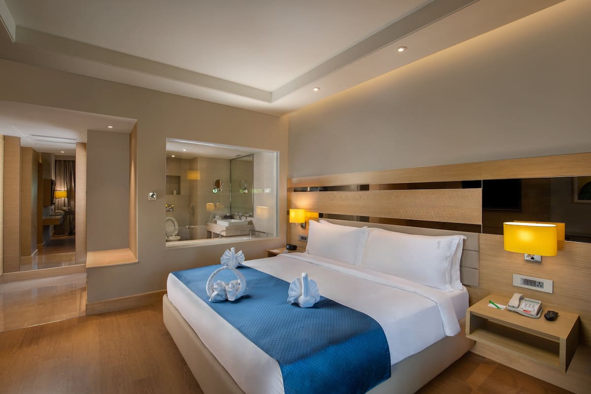 Una habitación de hotel moderna con una cama grande, lámparas de noche, una mesita de noche y un espejo.