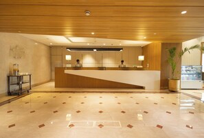 A reception area with a wooden reception desk, a glass display case, and a potted plant.