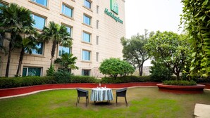 Une vue de l’extérieur d’un hôtel, avec une pelouse, deux chaises et une table.