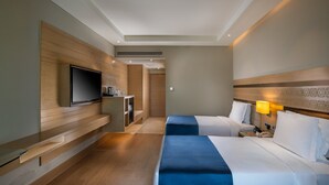 Une chambre d’hôtel avec deux lits, une télévision, un bureau et une lampe.