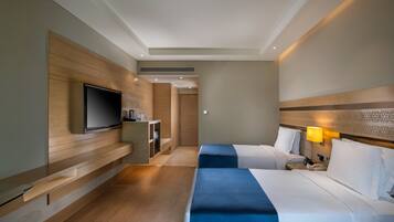 Una habitación de hotel con dos camas, televisor, escritorio y lámpara.