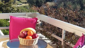 A balcony with a table and two chairs, one with a basket of fruit. - Vivian Studios (Rhodes)