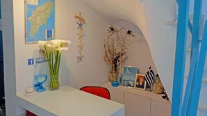 A reception desk with a map, a Facebook sign, a vase with white flowers, and a shelf with various items including a photo frame and a small American flag. - Vivian Studios (Rhodes)