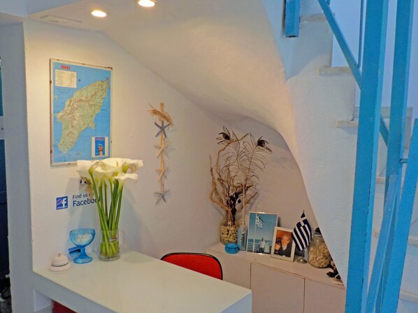 A reception desk with a map, a Facebook sign, a vase with white flowers, and a shelf with various items including a photo frame and a small American flag.
