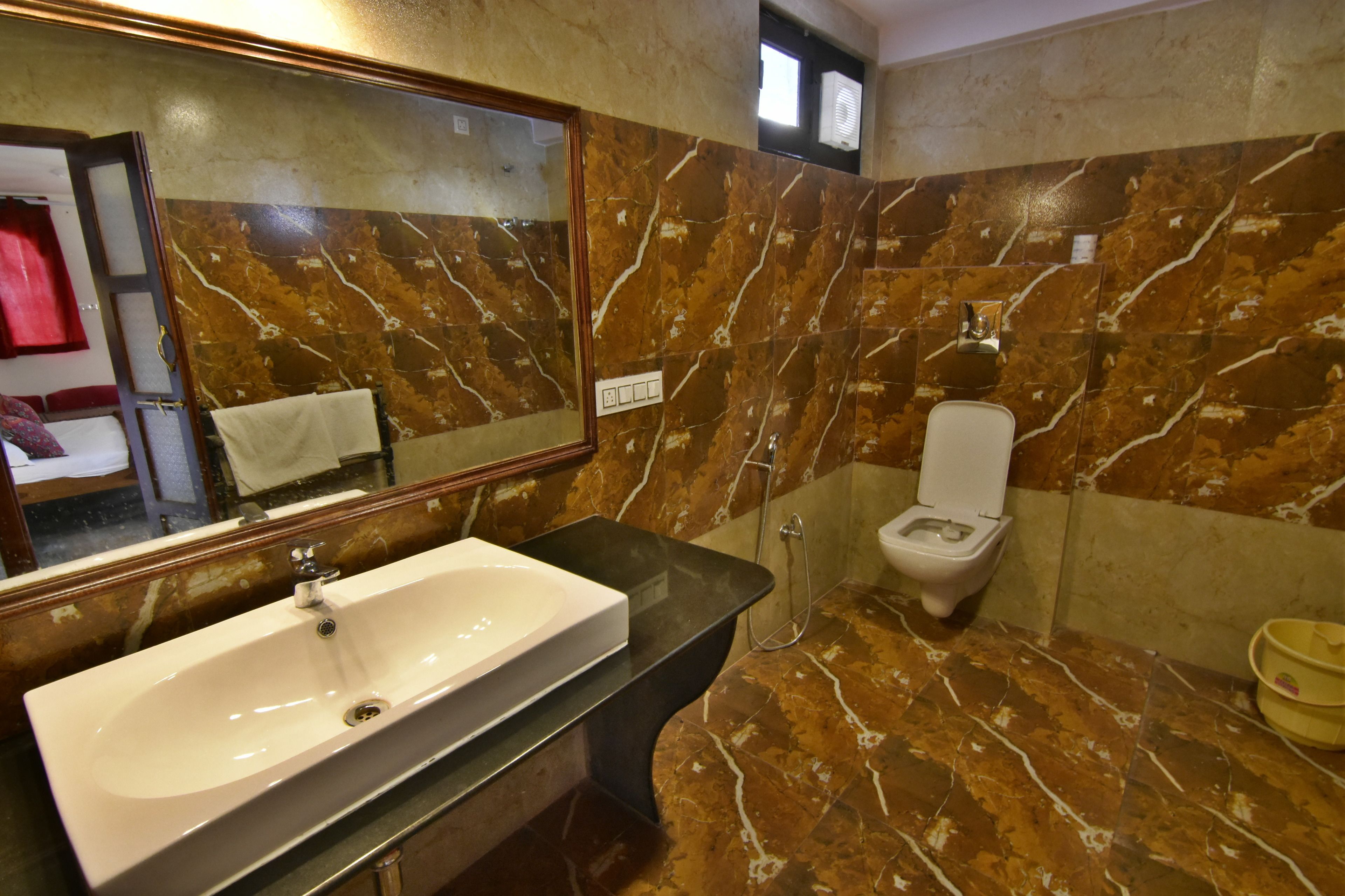 Un baño con salpicadero de mármol, un lavabo blanco, un inodoro y un espejo.