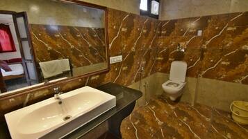 Un baño con salpicadero de mármol, un lavabo blanco, un inodoro y un espejo.