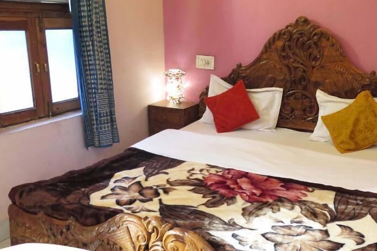 A bed with a floral bedspread, a wooden headboard, and a nightstand with a lamp.