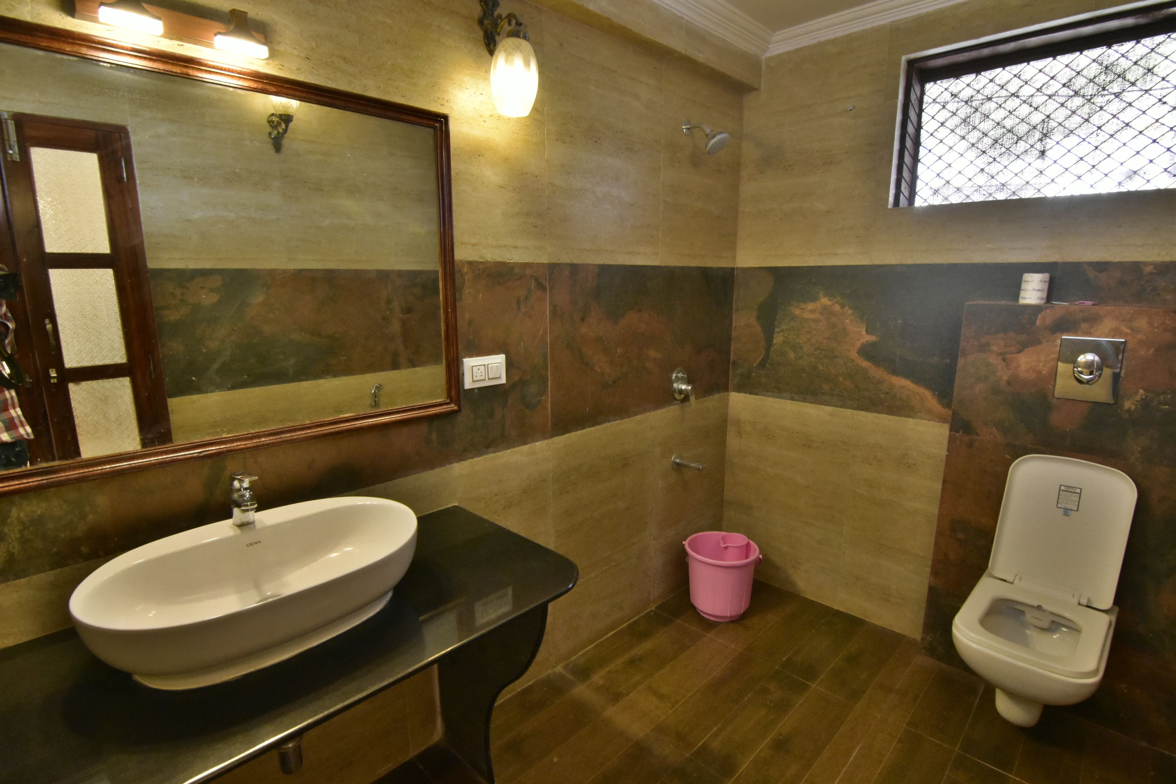 A bathroom with a large mirror, a sink, a toilet, and a shower.