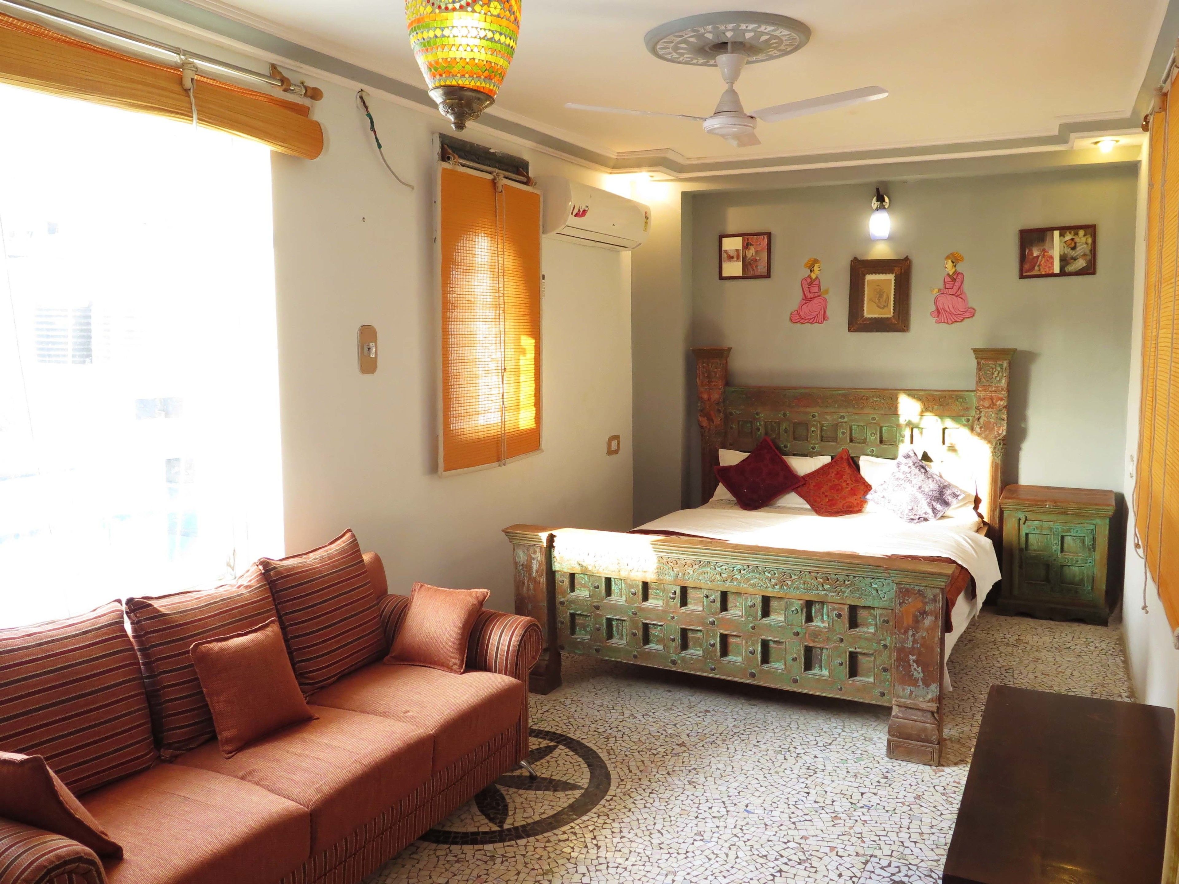 A room with a bed, a sofa, a ceiling fan, and a decorative lamp.