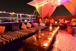 A cozy outdoor seating area with a sofa, cushions, and a table with candles. - Yogi Guest House (Jodhpur)