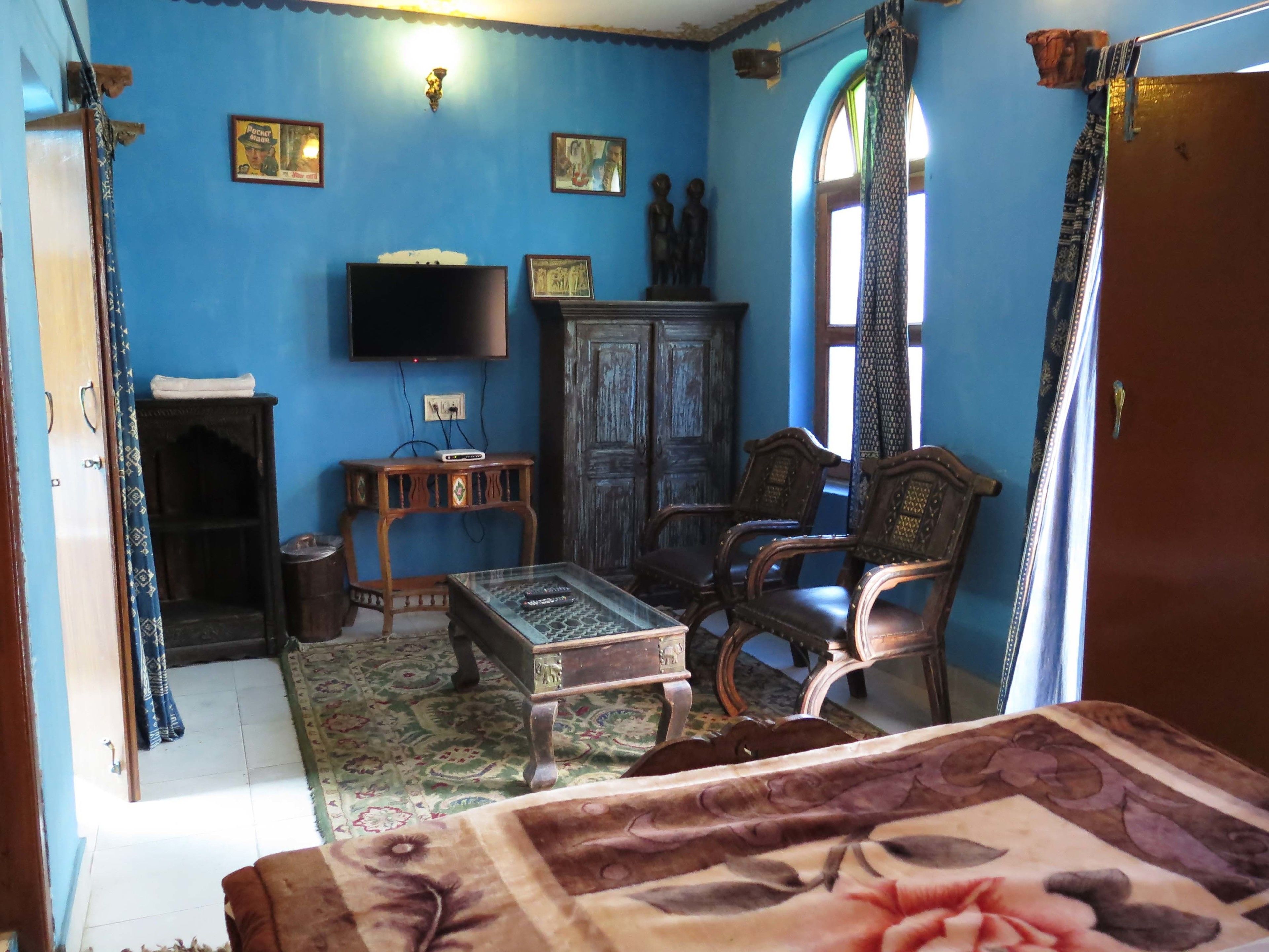 Een kamer met een blauwe muur, een televisie, een kast, een bank en een kamerbreed tapijt met een patroon.