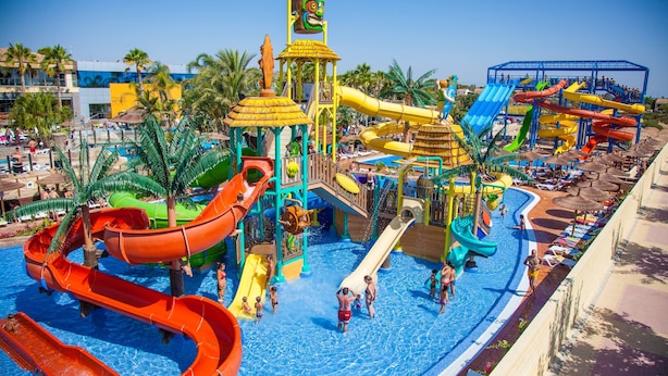 A water park with multiple slides and pools, surrounded by palm trees and lounge areas. - La Marina Resort (Elche)