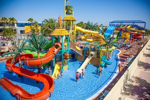 A water park with multiple slides and pools, surrounded by palm trees and lounge areas. - La Marina Resort (Elche)