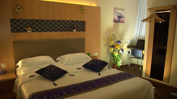 Een hotelkamer met een groot bed, een bureau met een laptop, een stoel en een garderobe.