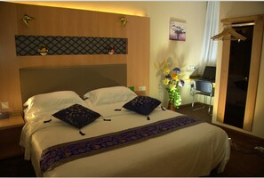 A hotel room with a large bed, a desk with a laptop, a chair, and a wardrobe. - Home Club Hotel Yuexiu Branch (Guangzhou)