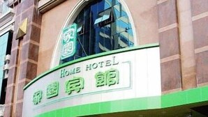 Een hotel met een geel-wit gevel, een groot rondboogvenster en een bord met zowel Engelse als Chinese tekst.
